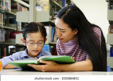 Young Mother Reading Books With  Kid At Home. Young Teacher Teaching Boy Kids At The School. The Tutor With Young  Student In The Library 