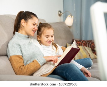 Young mother reads an interesting book for her small daughter