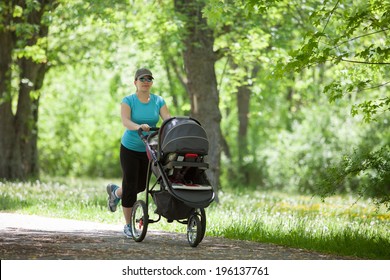 Young Mother Running While Pushing A Stroller In The Park