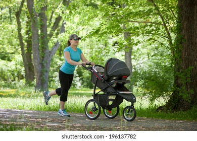 Young Mother Running While Pushing A Stroller In The Park