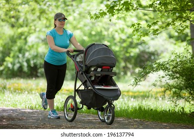 Young Mother Running While Pushing A Stroller In The Park