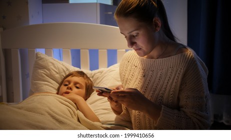 Young Mother Searching Medicines For Sick Child On Smartphone At Night.