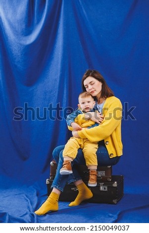A young mother sits with a son in her arms, family relationships with a child. Children's education. Mom with son on a blue background