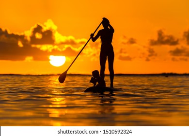 Young mother with a small child ride a S.U.P. (paddle) board in the Indian Ocean on the background of an incredible sunset - Powered by Shutterstock