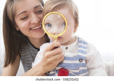 Young mother and son looking through a magnifying glass. Little boy with magnifying glass.