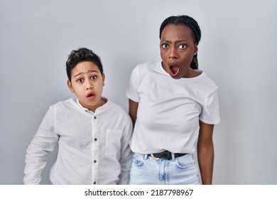 Young Mother And Son Standing Together Over White Background In Shock Face, Looking Skeptical And Sarcastic, Surprised With Open Mouth 