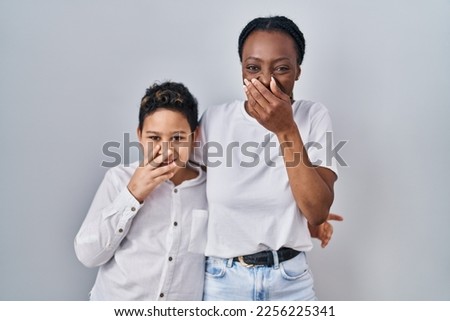 Young mother and son standing together over white background laughing and embarrassed giggle covering mouth with hands, gossip and scandal concept  Сток-фото © 