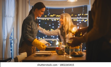 Young Mother Takes Casserole Dish Out Of Oven And Puts It On A Table. Happy Family Celebrating Together, Gathering Around Table With Delicious Dinner Meal.