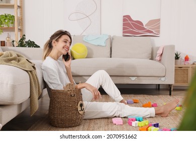 Young Mother Talking On Phone In Messy Living Room