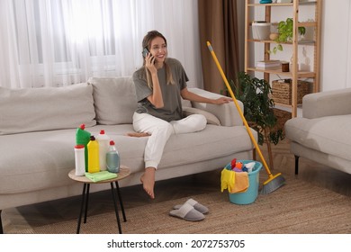 Young Mother Talking On Phone In Messy Living Room