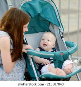 Young mother talking to smiling baby in a stroller