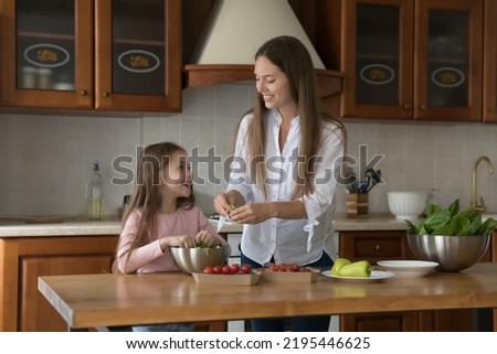 Young mother teach her little cute daughter to cook. Parent caring about health, cooking balanced natural dietary food, prepare together with child vegetarian dish in kitchen at home. Cookery Foto stock © 
