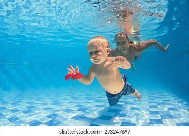 Young Mother Teaches To Swim 10 Month Old Baby - Dive With Cheerful Child Deep Into The Water For Red Flower, Healthy Lifestyle And Children Underwater Swimming Lessons With An Instructor In The Pool