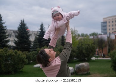 Young Mother Throws Up Baby In The Sky, Summer Outdoors.