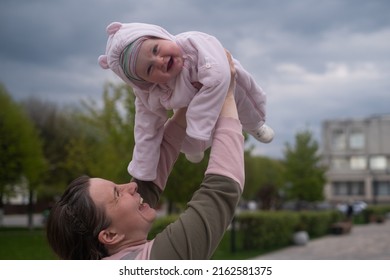 Young Mother Throws Up Baby In The Sky, Summer Outdoors.