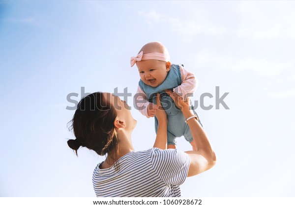 若い母親は夏の屋外空に赤ちゃんを放り出す 幸せな母親とかわいい笑顔の赤ちゃん 前向きな人間の感情 感情 自然の生き方 家族の背景 の写真素材 今すぐ編集