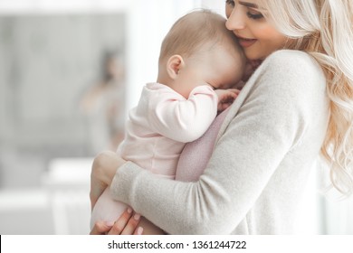 Young Mother Trying To Calm Down Her Little Crying Baby. Cute Child Wants To Eat And Sleep.