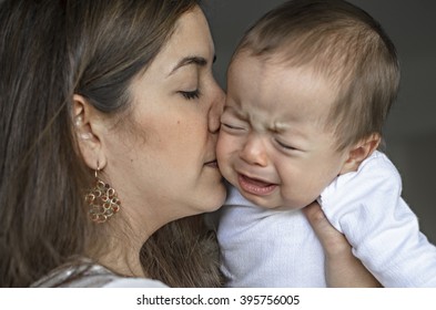 Young Mother Trying To Comfort And Calm Down Her Baby Boy.