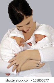 Young Mother With Twin Babies In White Clothing