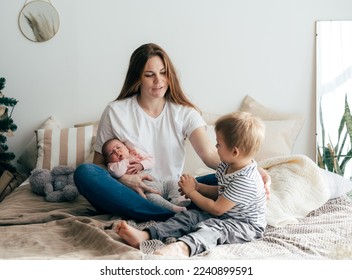 A young mother with two small children spends time in the bedroom at home. - Shutterstock ID 2240899591