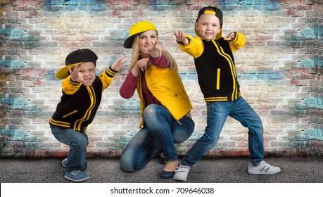 A Young Mother And Two Young Sons In The Style Of Hip Hop.Fashionable Family.Graffiti On The Walls.	