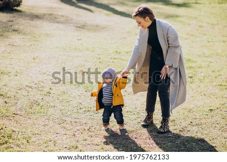 Young mother walking with her little toddler son in park