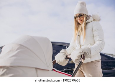 Young Mother Walking With Her Newborn Baby In Stroller In Winter Time