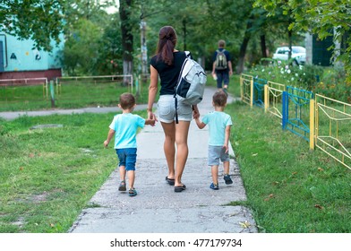 Young Mother Walking And Holding Hands Two Boys