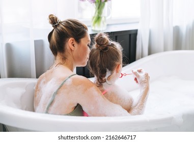 Young Mother Woman And Little Tween Girl Daughter Having Fun In Bath With Foam At Home