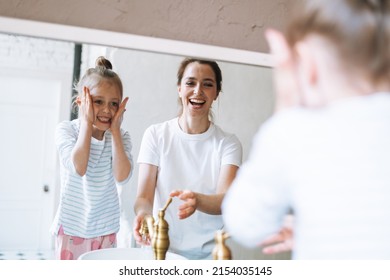 Young Mother Woman With Long Hair With Little Tween Girl Daughter In Pajamas Washing Face And Hands In The Morning At Home, Family Spending Time Together In Bathroom