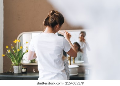 Young Mother Woman With Long Hair With Little Tween Girl Daughter In Pajamas Combs Her Hair On Morning In Bathroom At Home