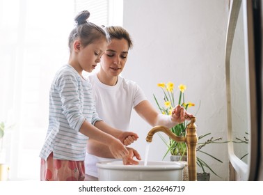 Young Mother Woman With Long Hair With Little Tween Girl Daughter In Pajamas Washing Face And Hands In The Morning At Home, Family Spending Time Together In Bathroom