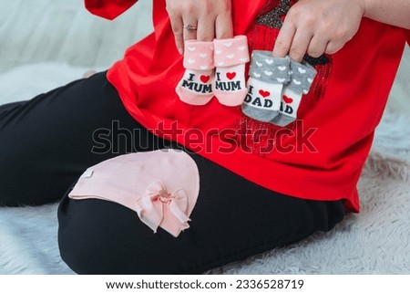 young mother with women's socks in her hand. pregnant girl with socks for a newborn baby. photo session of a pregnant woman in a photo studio