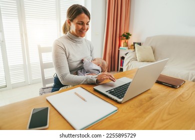 Young mother working at home while feeding her infant son - Smart working and family concept - Focus on mom face