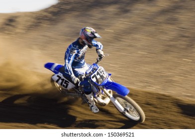 Young Motocross Racer Riding Motorcycle On Dirt Track