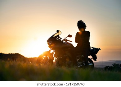 Young Motorcycle Rider On The Road With Sunset Light Background.