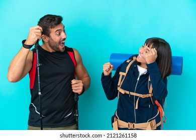 Young mountaineer couple with a big backpack isolated on blue background celebrating a victory in winner position - Powered by Shutterstock