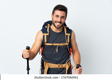 Young Mountaineer Man With A Big Backpack And Trekking Poles Isolated On White Background Laughing