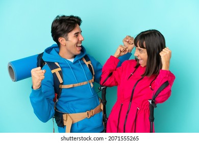 Young mountaineers couple isolated on blue background celebrating a victory in winner position - Powered by Shutterstock