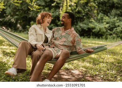 Young multi ethnic couple laughing and relaxing in hammock during summer vacation, enjoying quality time together in nature - Powered by Shutterstock