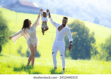 Young multi ethnic family portrait. Mixed race parents with baby spend time together hugs kisses in park. African american husband and caucasian wife and baby interracial child enjoying summer day. - Powered by Shutterstock