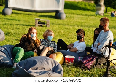 Young Multi Ethnic Group Of People Watching Movie At Poof In Open Air Cinema Wear At Mask During Covid Coronavirus Quarantine.