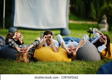 Young multi ethnic group of people watching movie at poof in open air cinema.