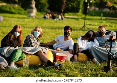 Young Multi Ethnic Group Of People Watching Movie At Poof In Open Air Cinema Wear At Mask During Covid Coronavirus Quarantine.