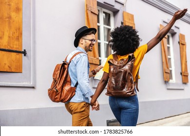 Young multicultural couple holding hands and visiting city. Man holding a map. - Powered by Shutterstock