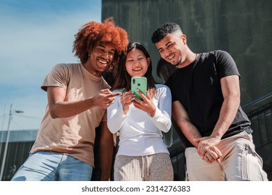 Young multicultural teenagers watching funny images on a smart phone. Three smiling young adult people browsing on internet with a celphone app. Hppy students playing video games using a mobilephone - Powered by Shutterstock