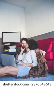 young multiethnic couple indoor using computer sitting floor