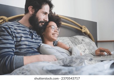 young multiethnic couple indoor using computer sitting bed  