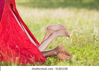young multiethnic couple lying in tent with feet crossed. Copy space