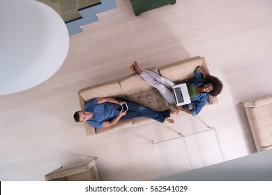 Young Multiethnic Couple Relaxes In The Luxury Living Room, Using A Tablet And Laptop Computer Top View